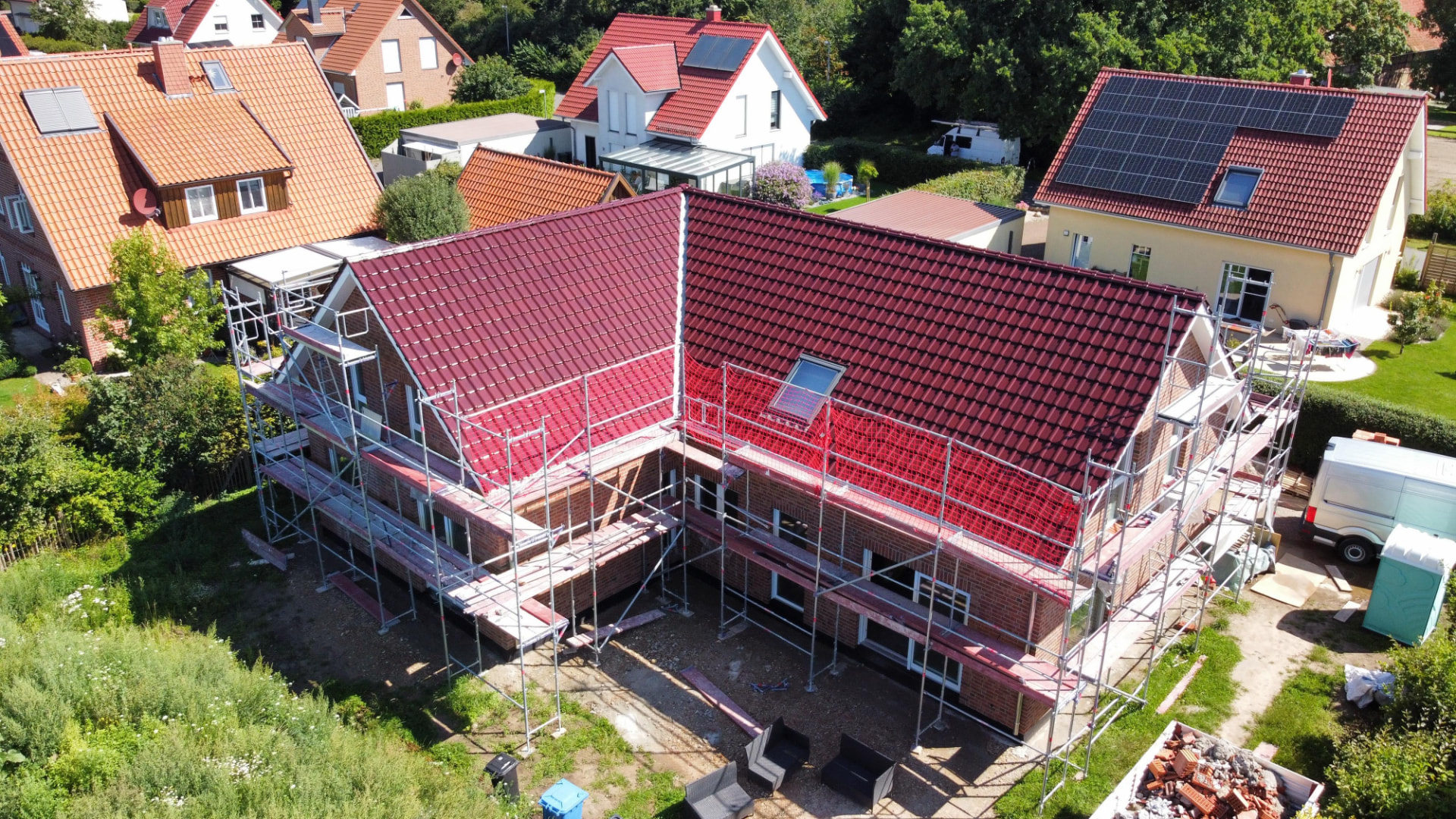 Haus mit frisch eingedecktem Steildach aus roten Dachziegeln und einem Dachfenster